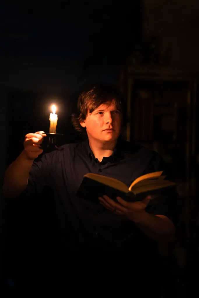 An adventurer exploring a library by candlelight.